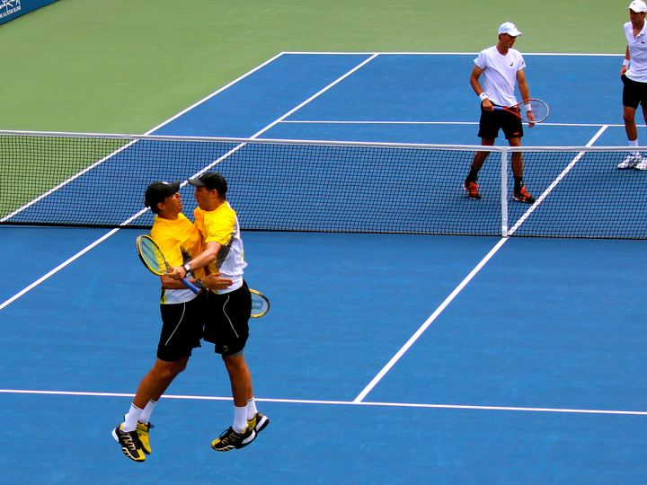 Twin tennis players Bob and Mike Bryan leaping into a mid-air chest bump on court after winning a match at the US Open