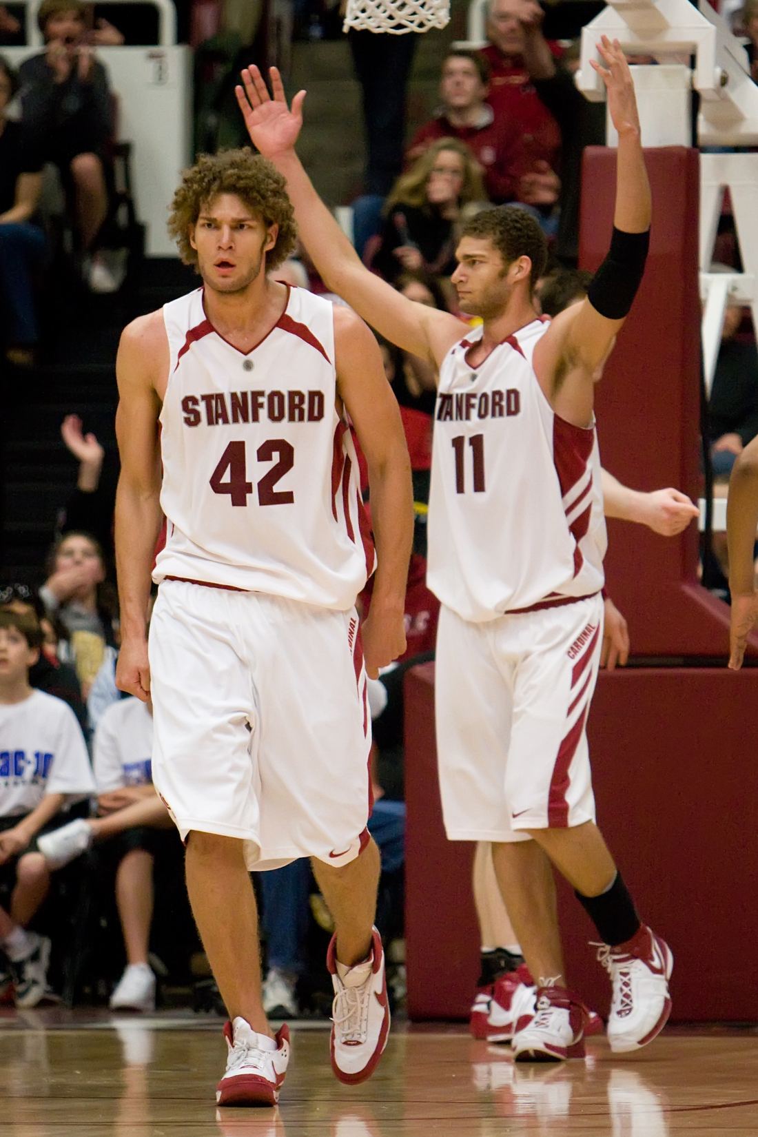 Robin and Brook Lopez, tall twin basketball players, standing side by side in Stanford team gear