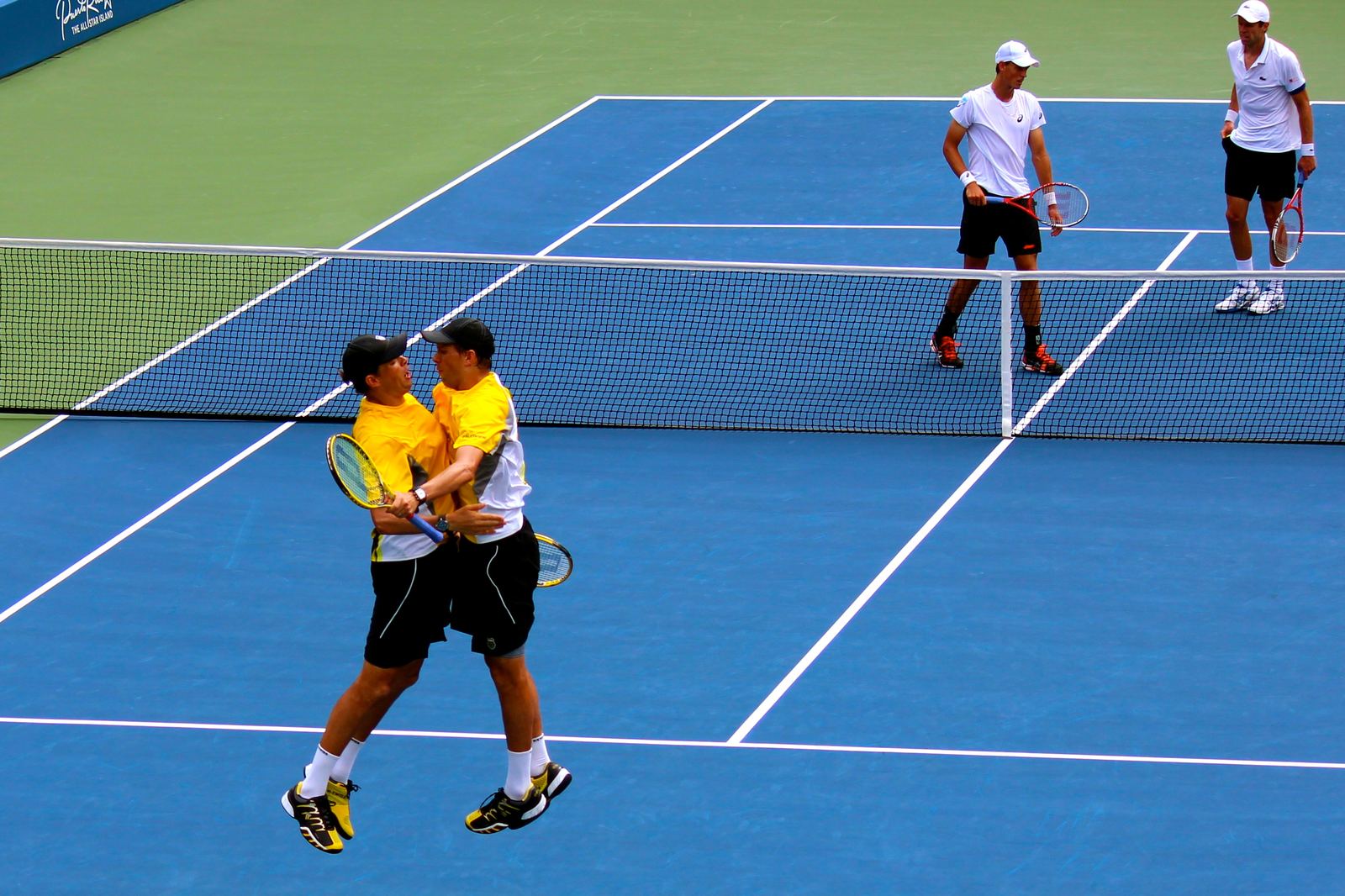 Twin tennis players Bob and Mike Bryan leaping into a mid-air chest bump on court after winning a match at the US Open