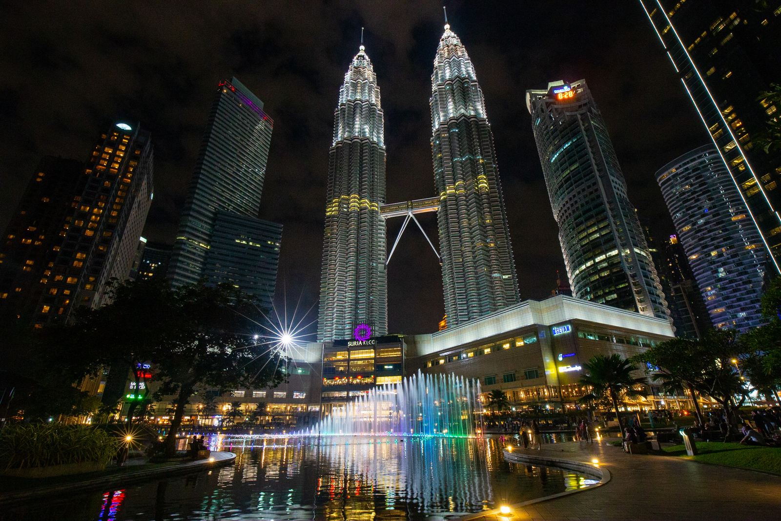 The Petronas Twin Towers in Kuala Lumpur glowing silver against a dark night sky, joined by a skybridge