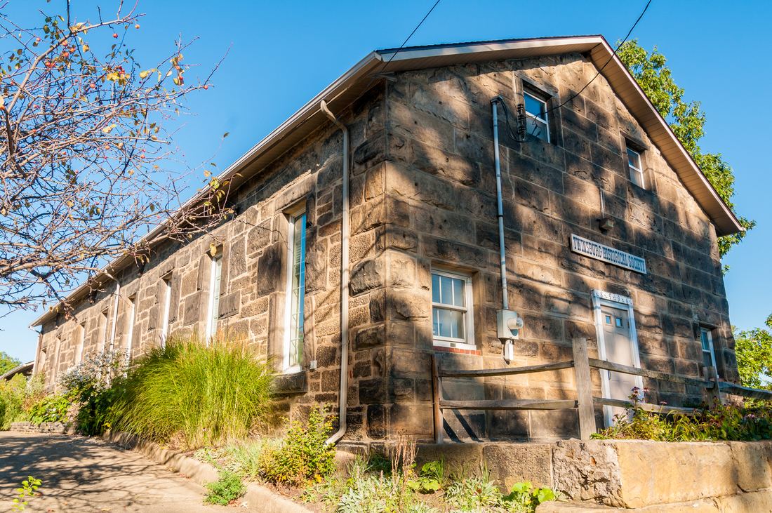 A long two-story sandstone building with a pitched roof and white windows, the old Twinsburg Institute, under a clear blue sky